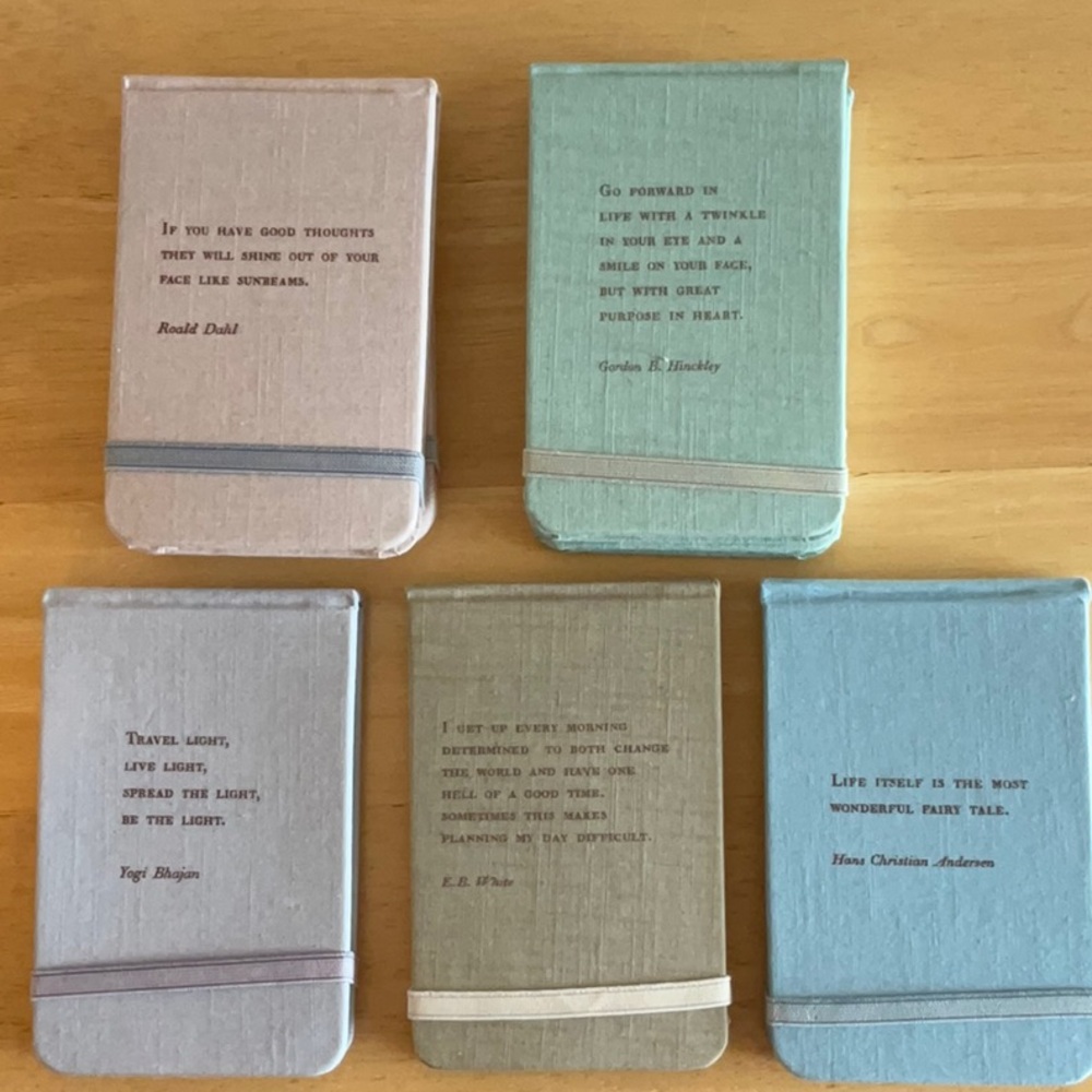 Set of 7 fabric covered notebooks with inspirational quote on cover.